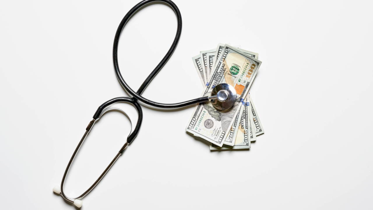 Фонендоскоп с долларами на белом фоне