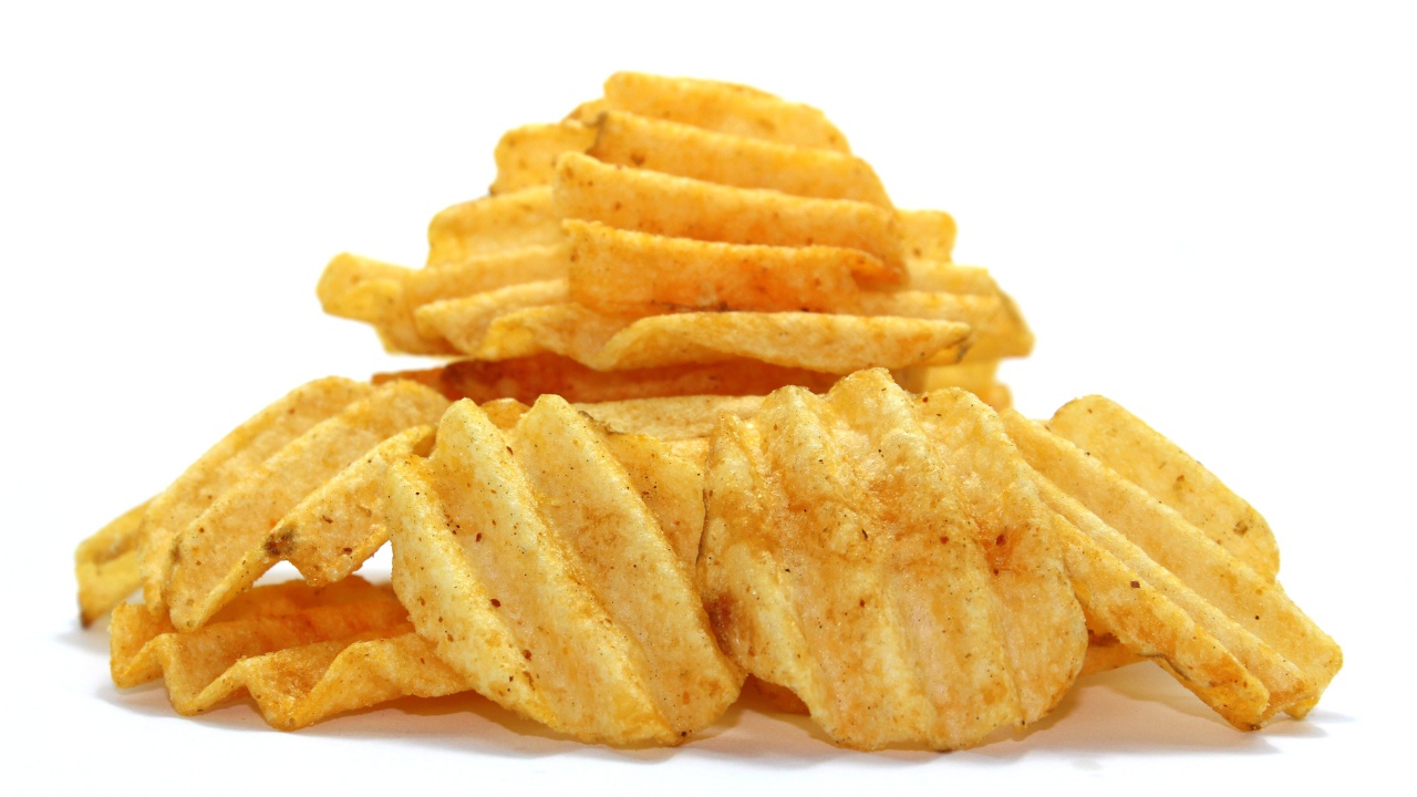 Аппетитные картофельные чипсы на сером фоне