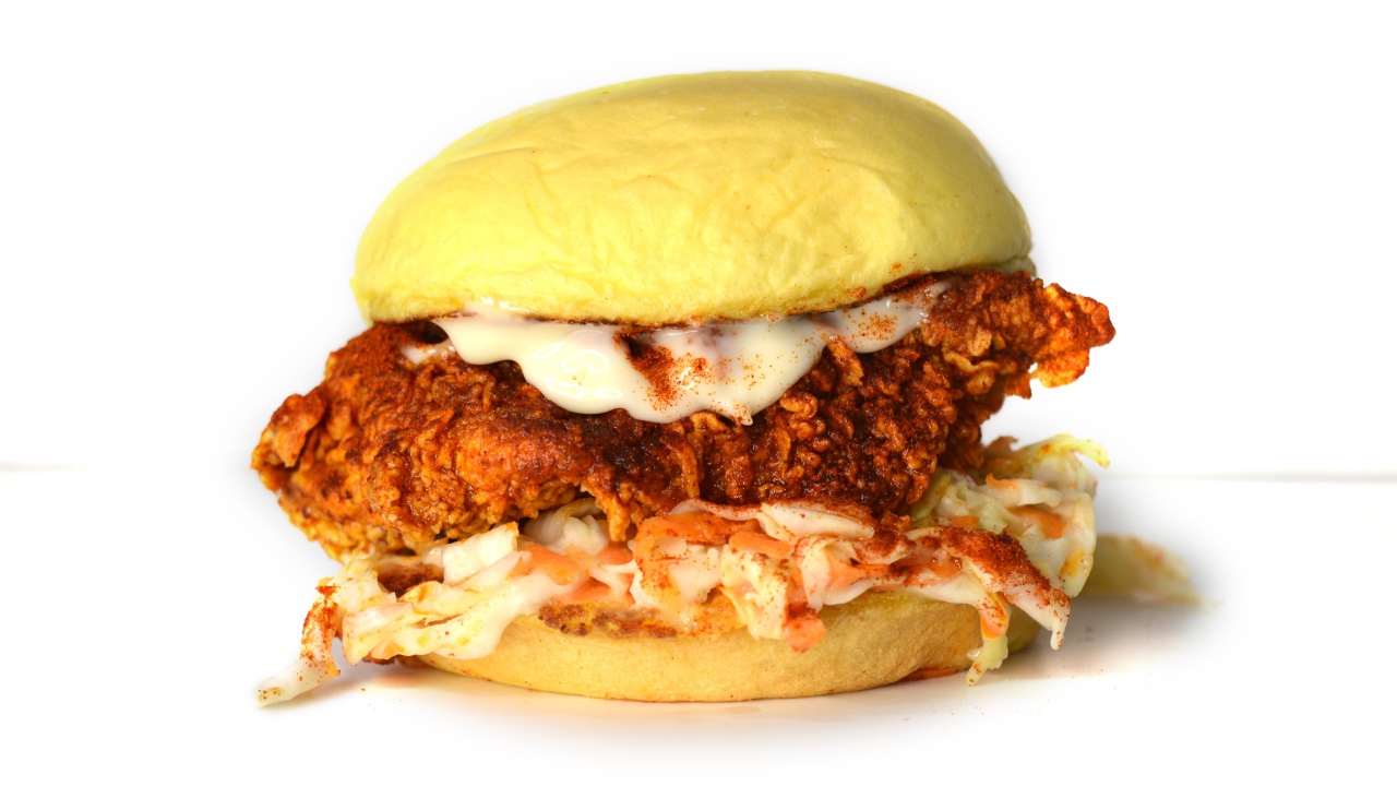 Большой куриный бургер с соусом на белом фоне