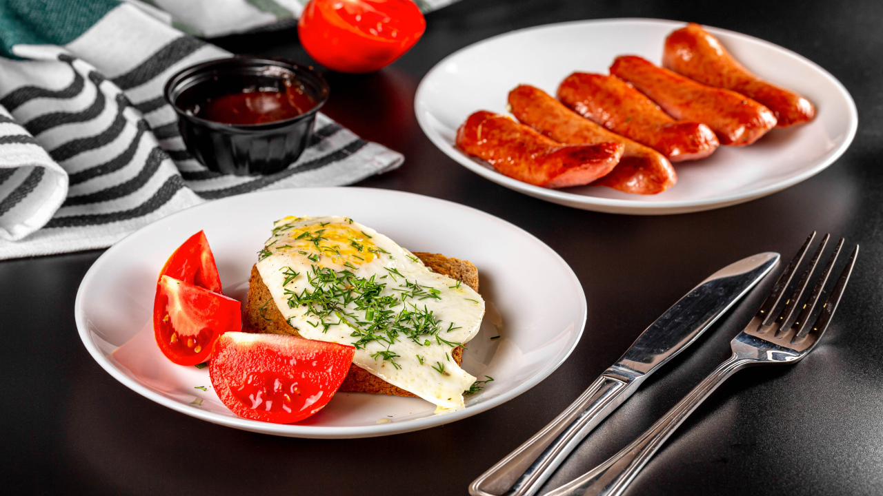 Хлеб с яичницей и помидорами на тарелке с сосисками