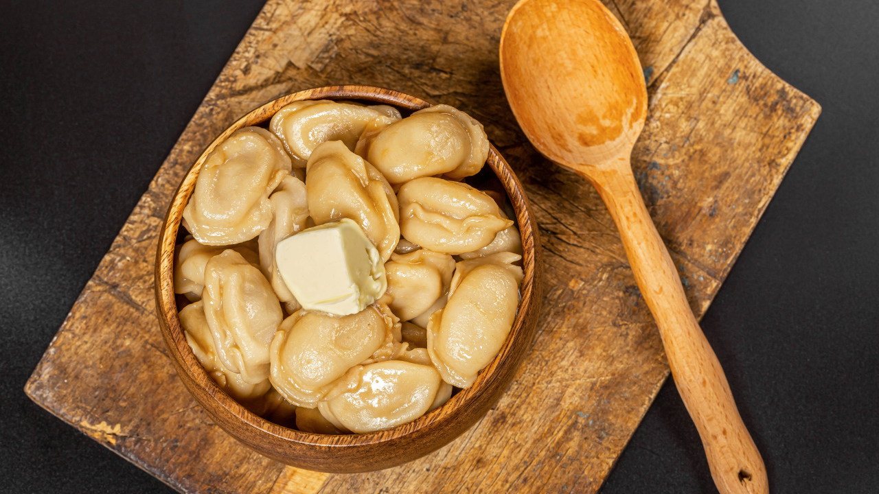 Пельмени в деревянной миске с маслом