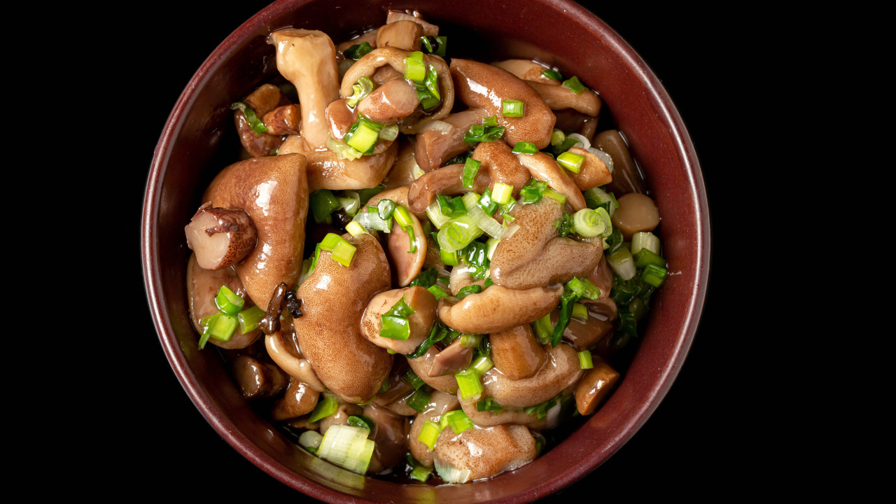 Маринованные маслята с зеленью в тарелке