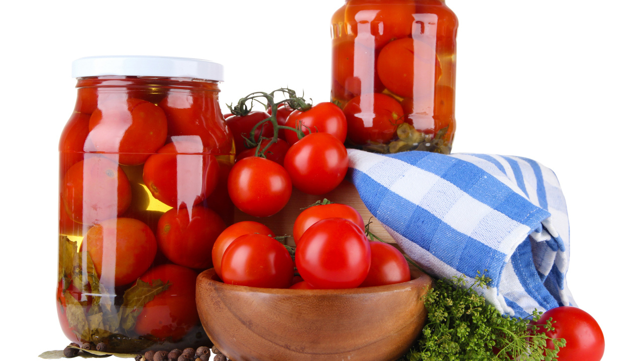 Маринованные помидоры в банках на столе со свежими