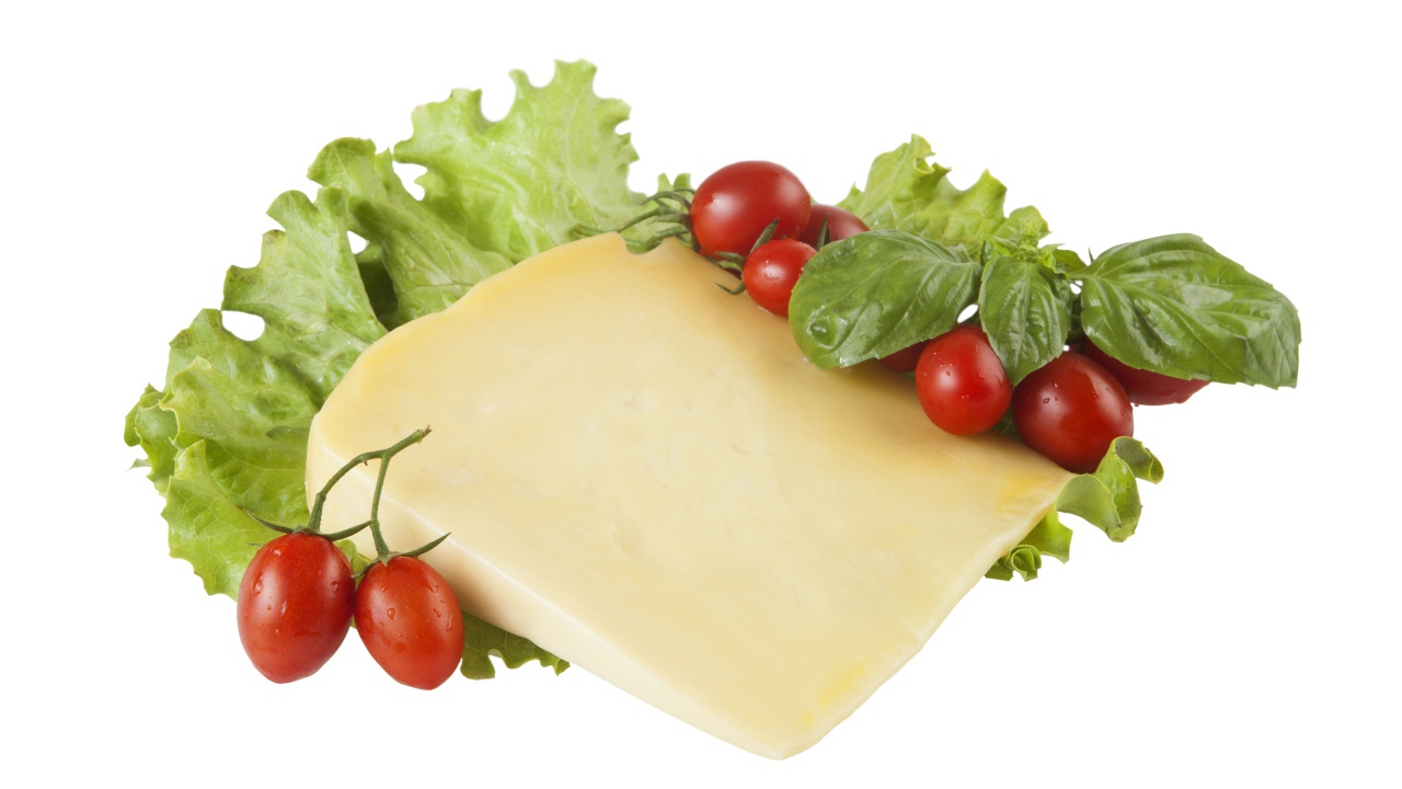 Кусок сыра с помидорами и листьями салата на белом фоне