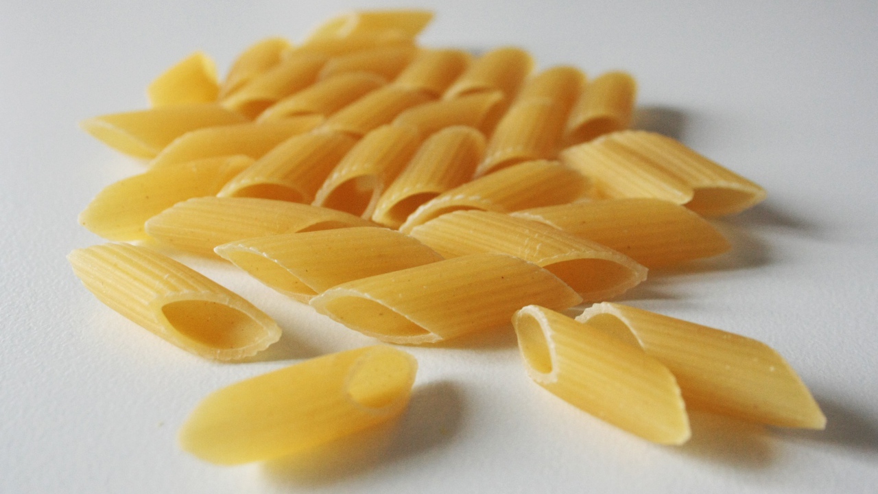 Сырые желтые макароны на сером фоне