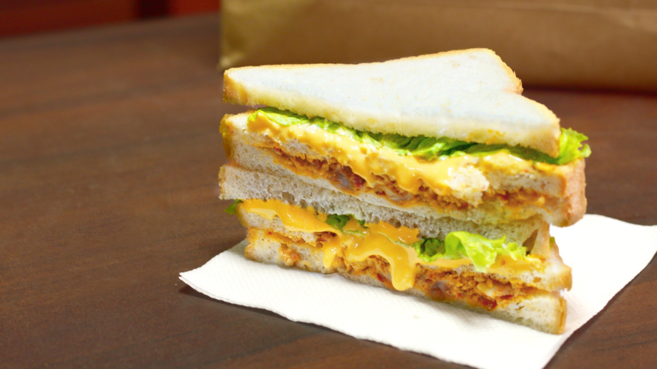 Сэндвич с сыром и листьями салата на столе