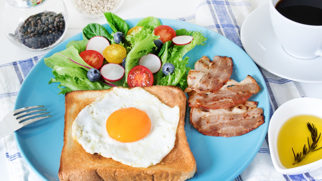 Яичница с хлебом на тарелке с салатом и беконом 