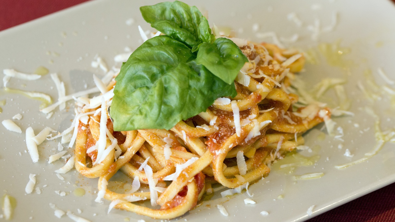 Spaghetti with cheese and basil leaves