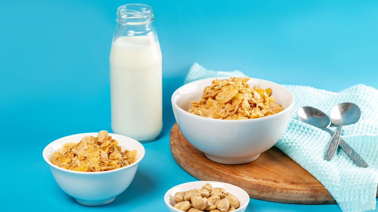 Хлопья на столе с орехами и молоком на голубом фоне