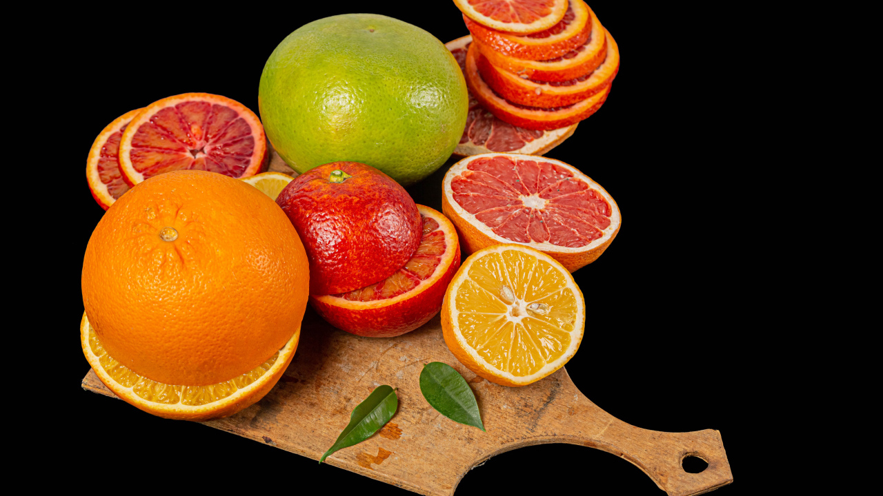 Свежие нарезанные цитрусовые фрукты на черном фоне