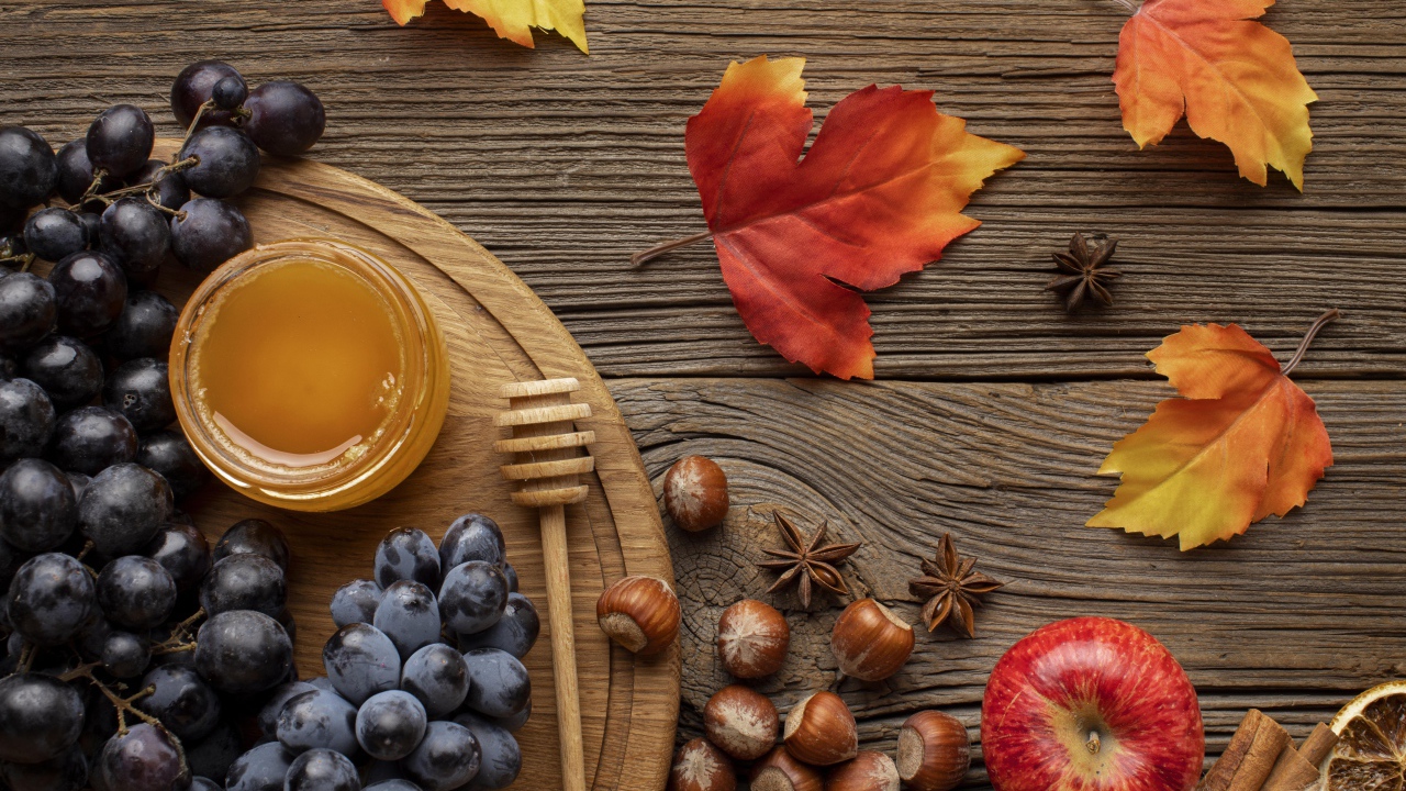 Мед на столе с виноградом, орехами и яблоками