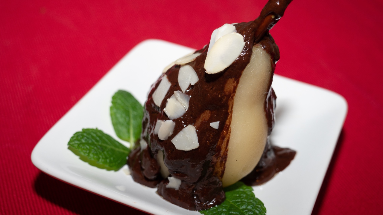 Pear on a white plate with chocolate on a red background