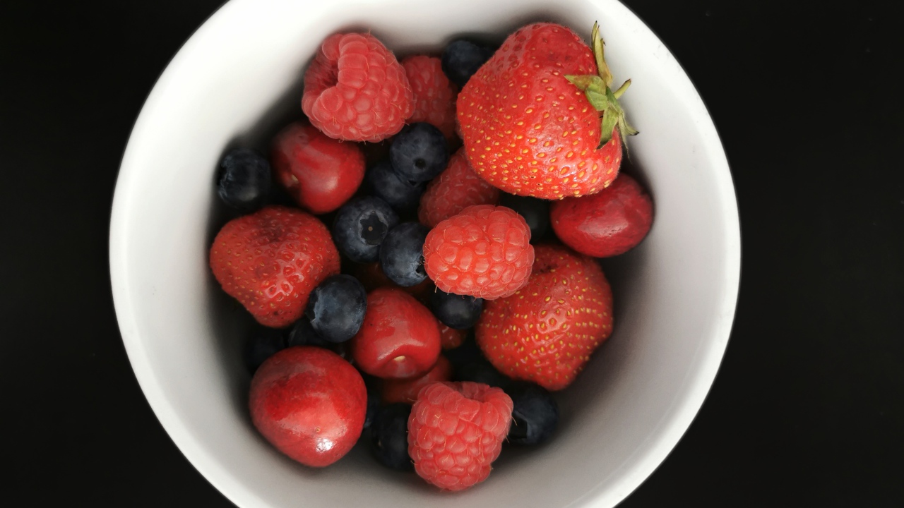 Спелые свежие ягоды в белой тарелке на белом фоне