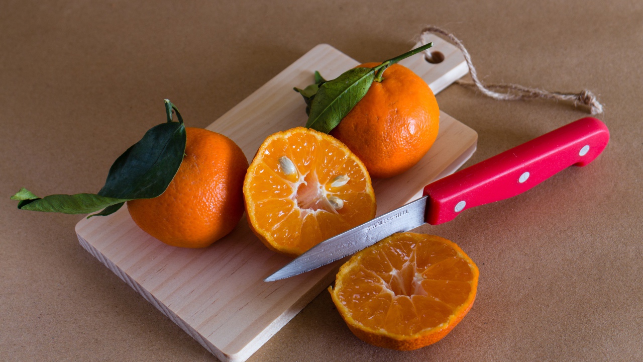 Мандарины лежат на доске с ножом 
