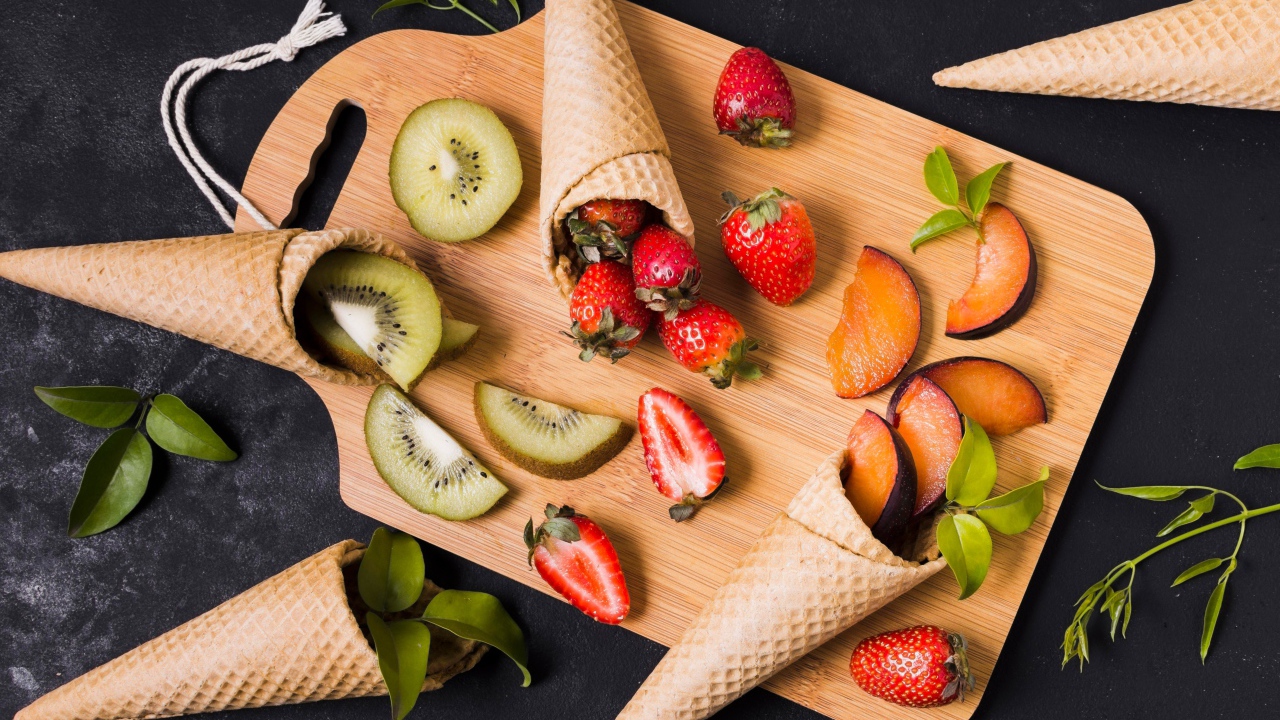 Вафельные рожки с ягодами и фруктами на доске 