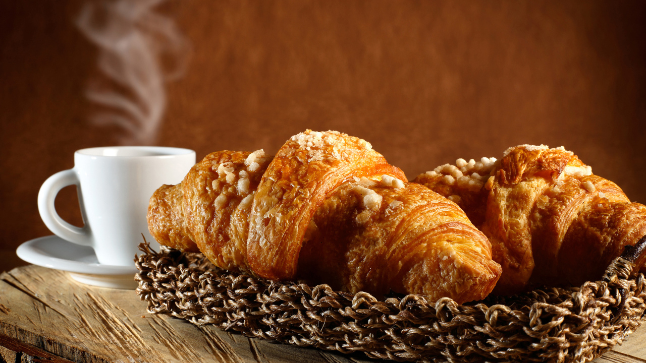 Два свежих круассана на столе с кофе 