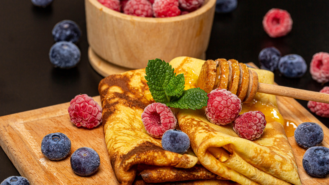 Аппетитные блины с малиной и черникой на столе