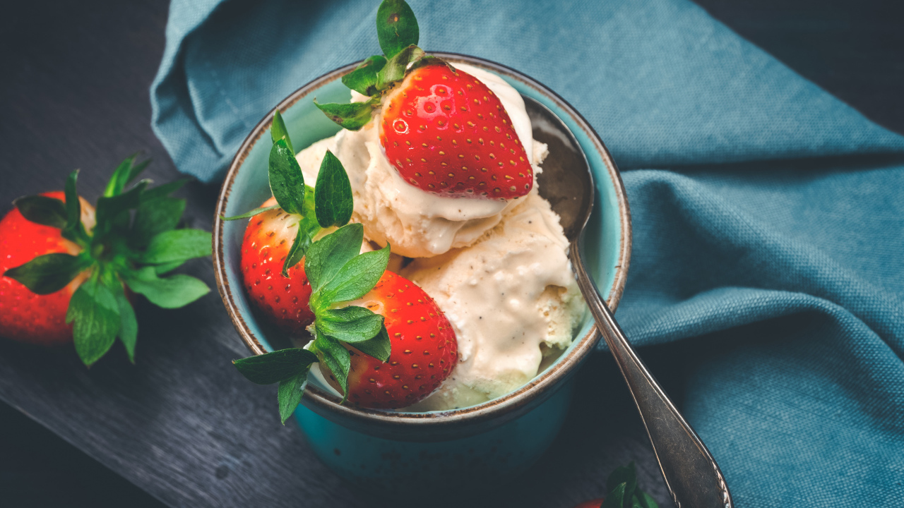 Сливочное мороженое с ягодами клубники в чашке с ложкой