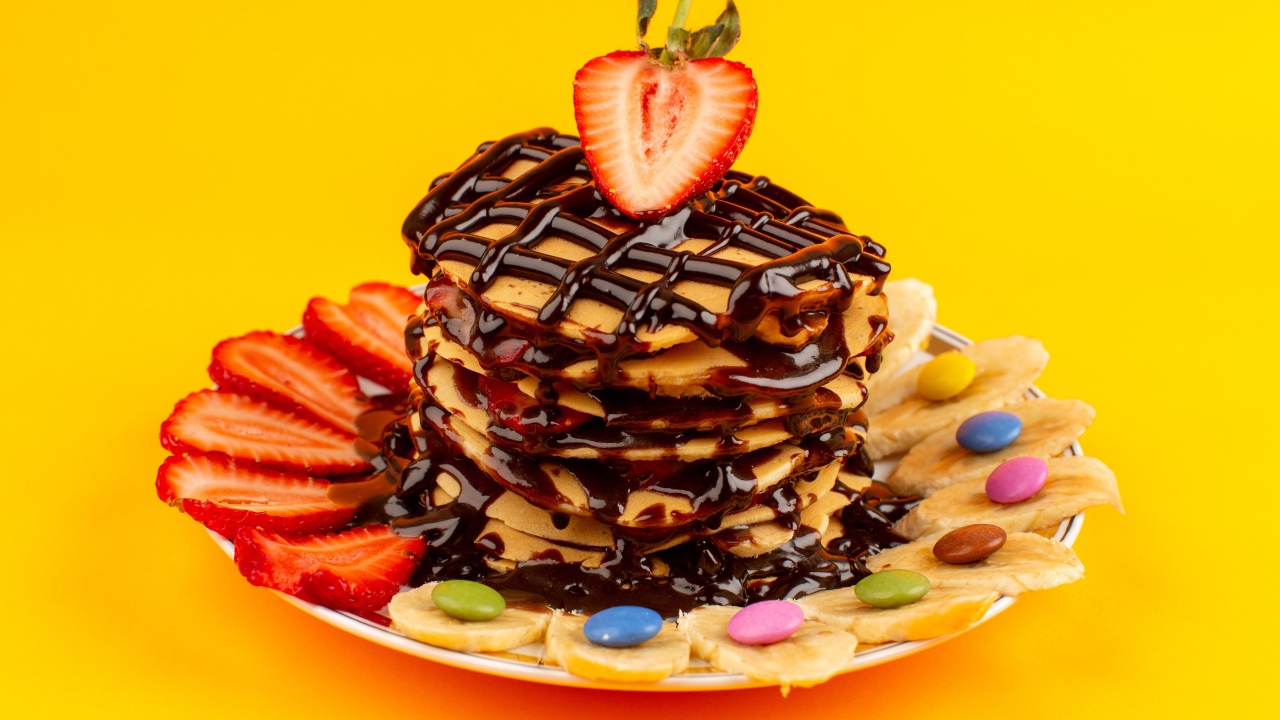 Оладьи с шоколадом, клубникой и бананом на желтом фоне 