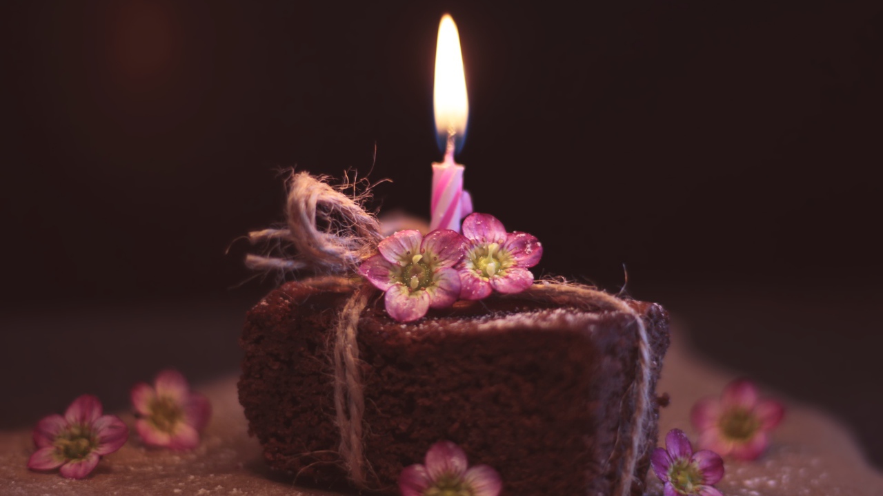 Кусок торта на столе с розовыми цветами и свечкой