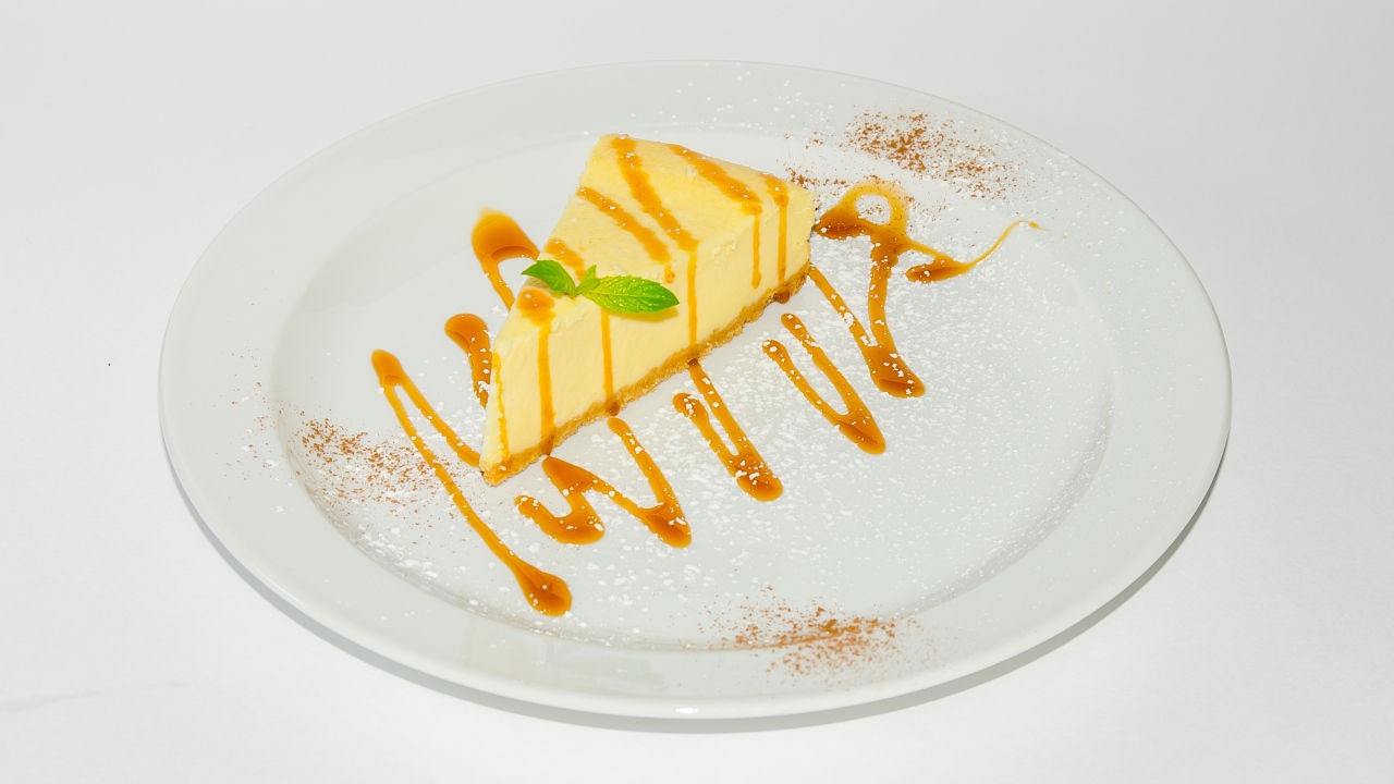 Кусок чизкейка с сиропом на большой белой тарелке 