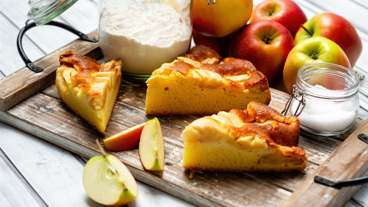 Куски пирога на столе с яблоками и мукой