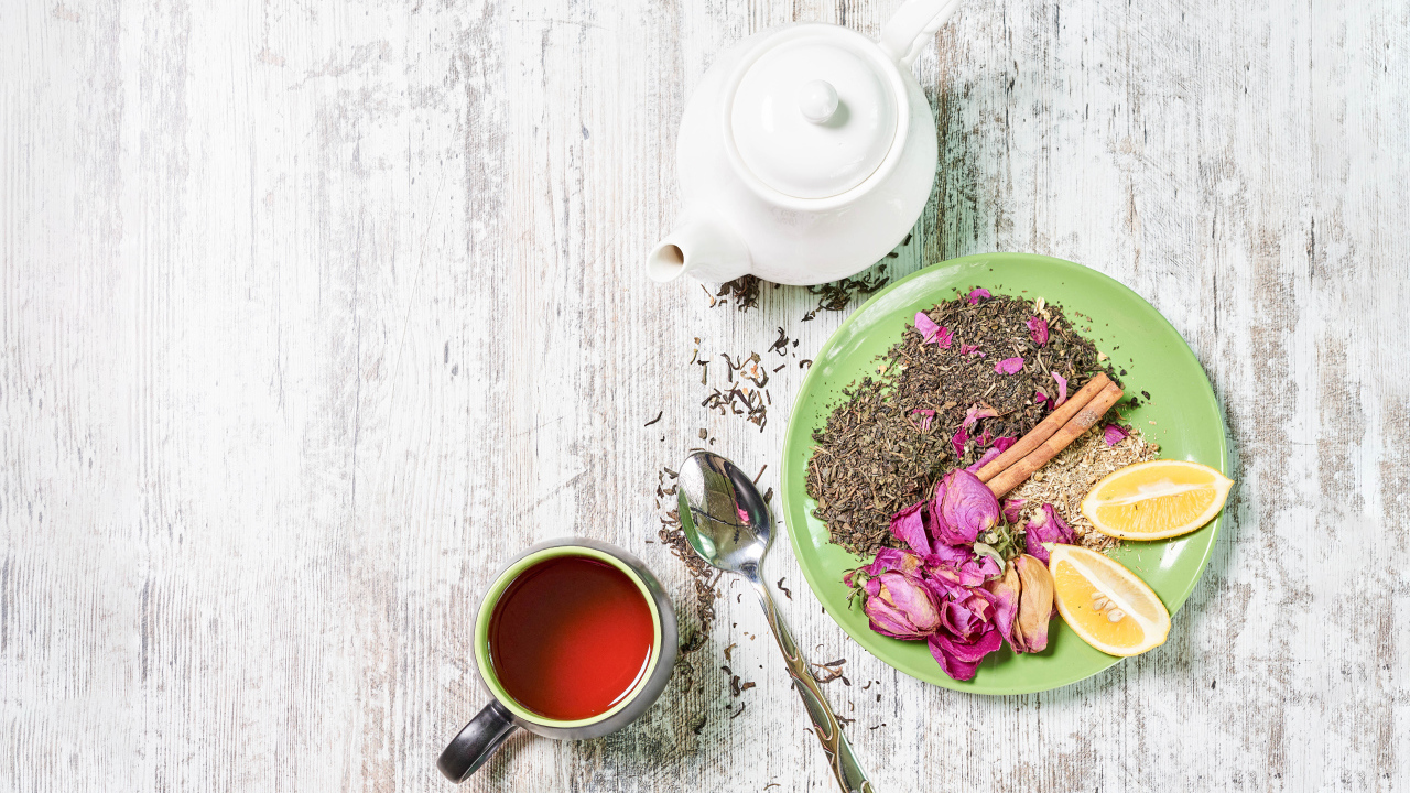 Чай на тарелке с кусочками лимона на столе