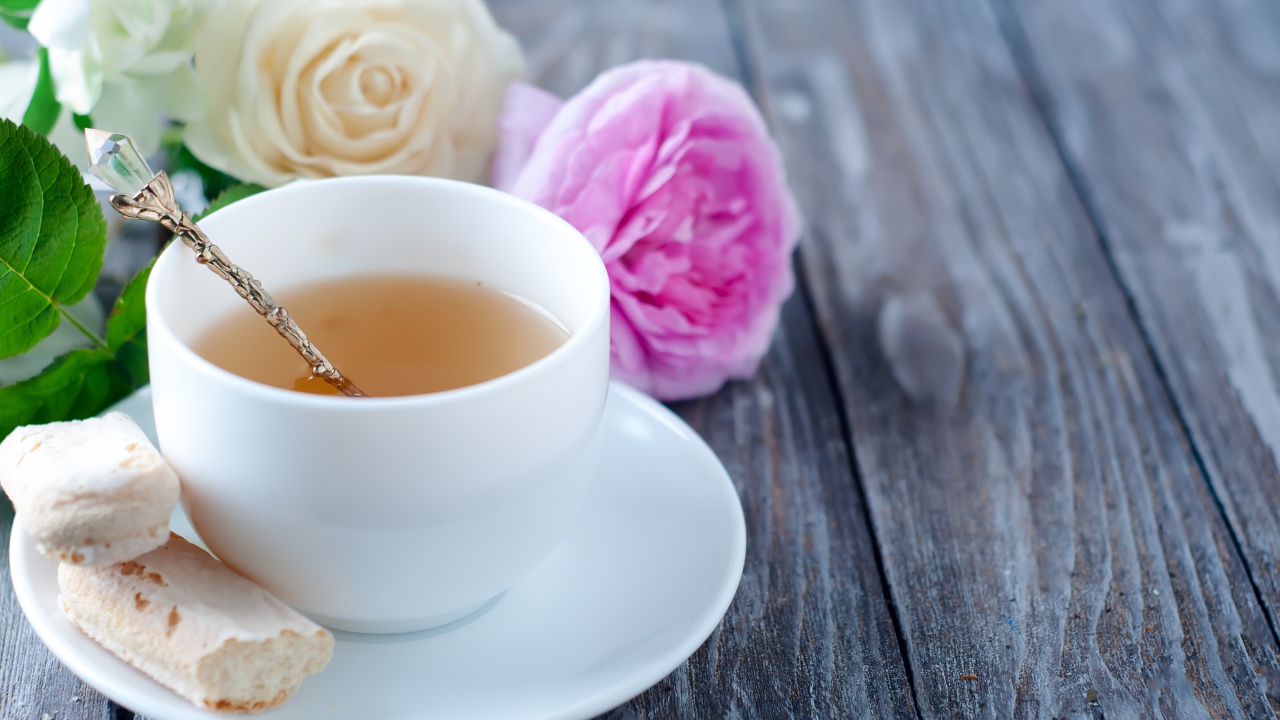 Белая чашка чая на деревянном  столе с розами