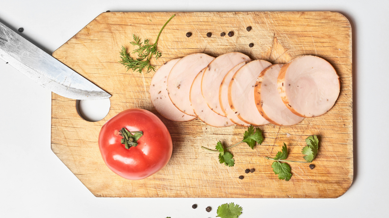 Ветчина на разделочной доске с помидором