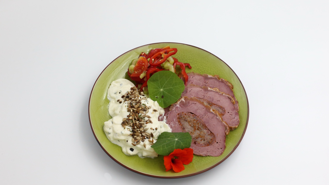 Мясо с соусом и овощами на тарелке на сером фоне