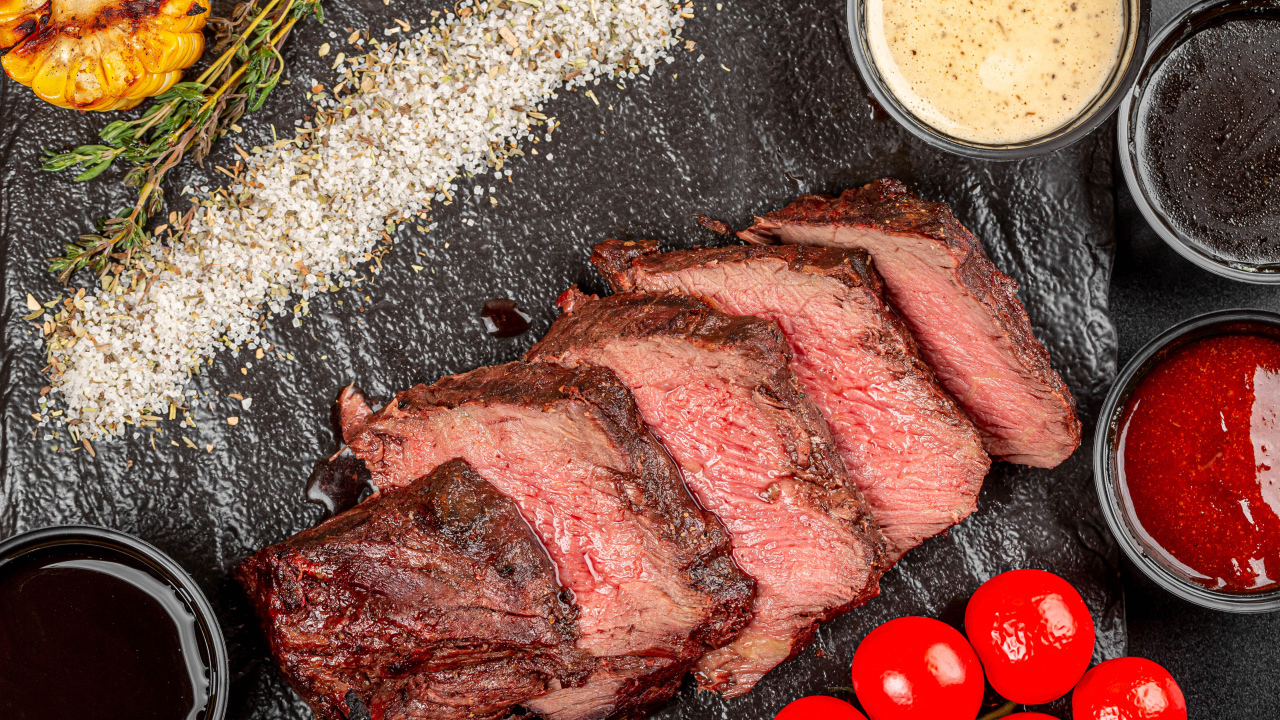 Мясо с помидорами и соусами на доске 