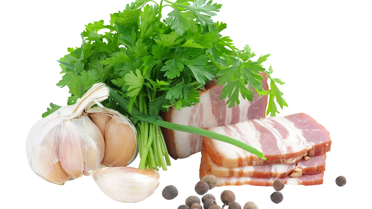 Кусок сала на белом фоне с зеленью петрушки и специями