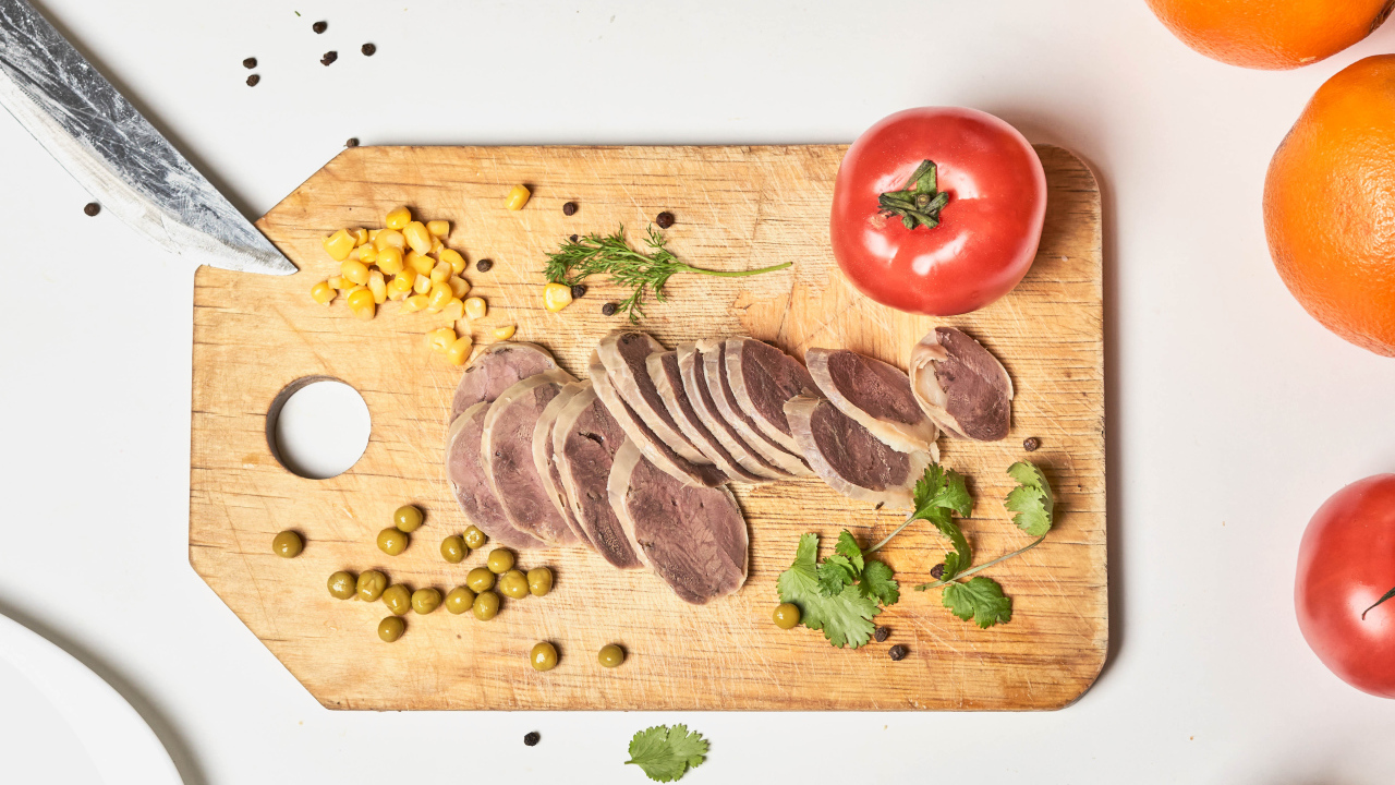 Sliced tongue with green peas on a board