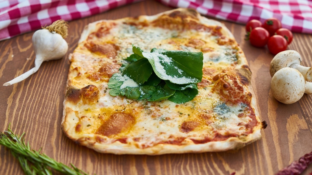 Румяная пицца на столе с овощами