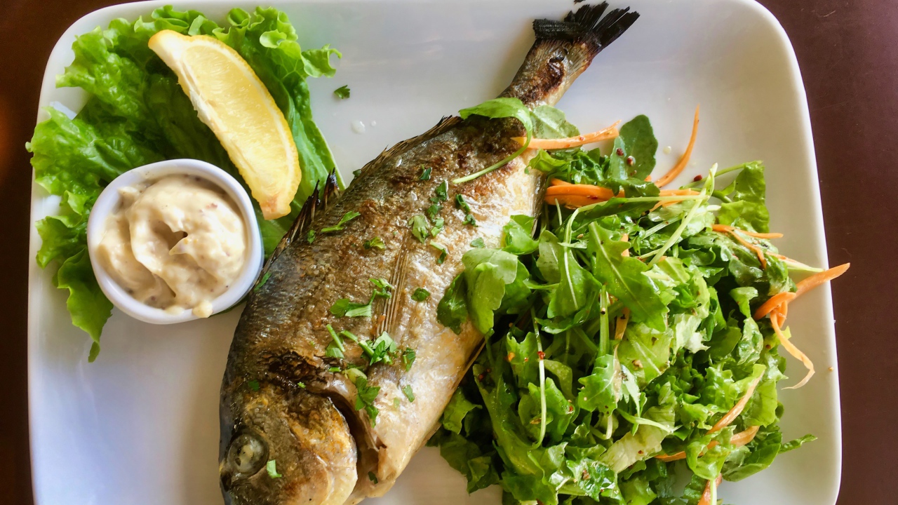 Жареный карась на тарелке с салатом 