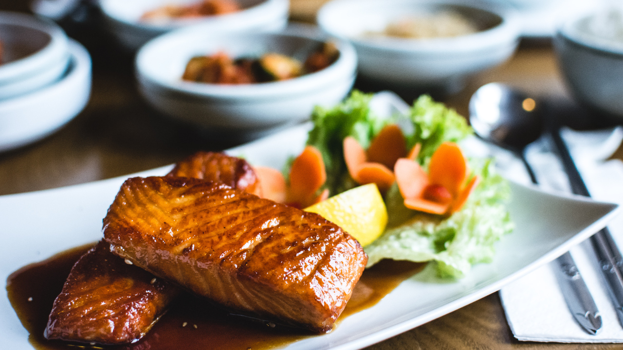 Два куска рыбы в соусе с овощами на тарелке