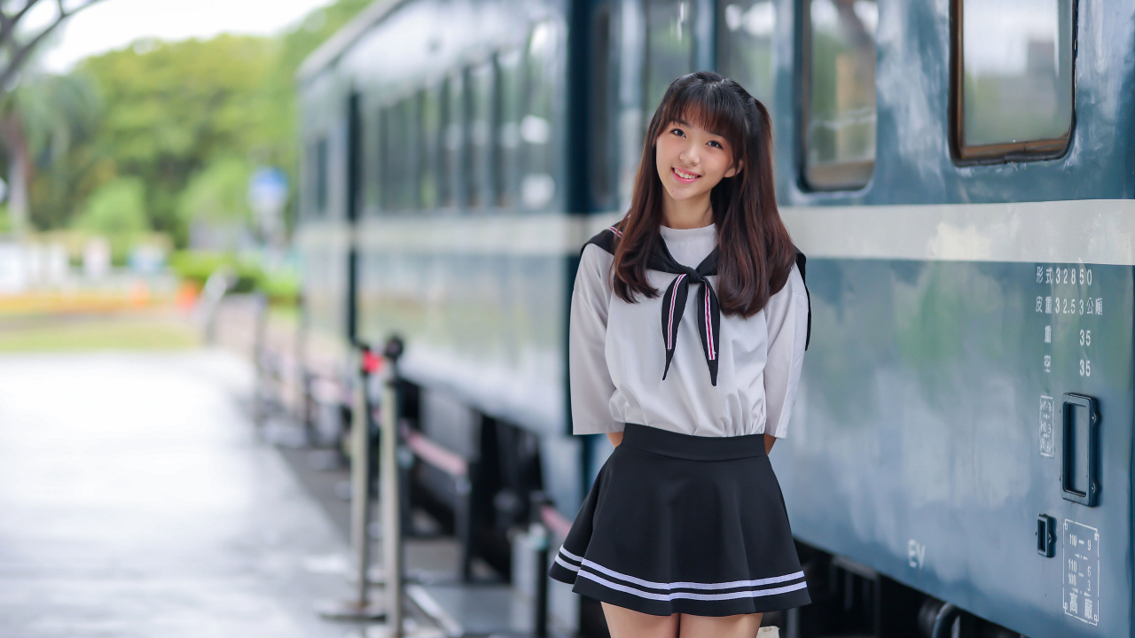 Красивая девушка азиатка в костюме стоит у поезда