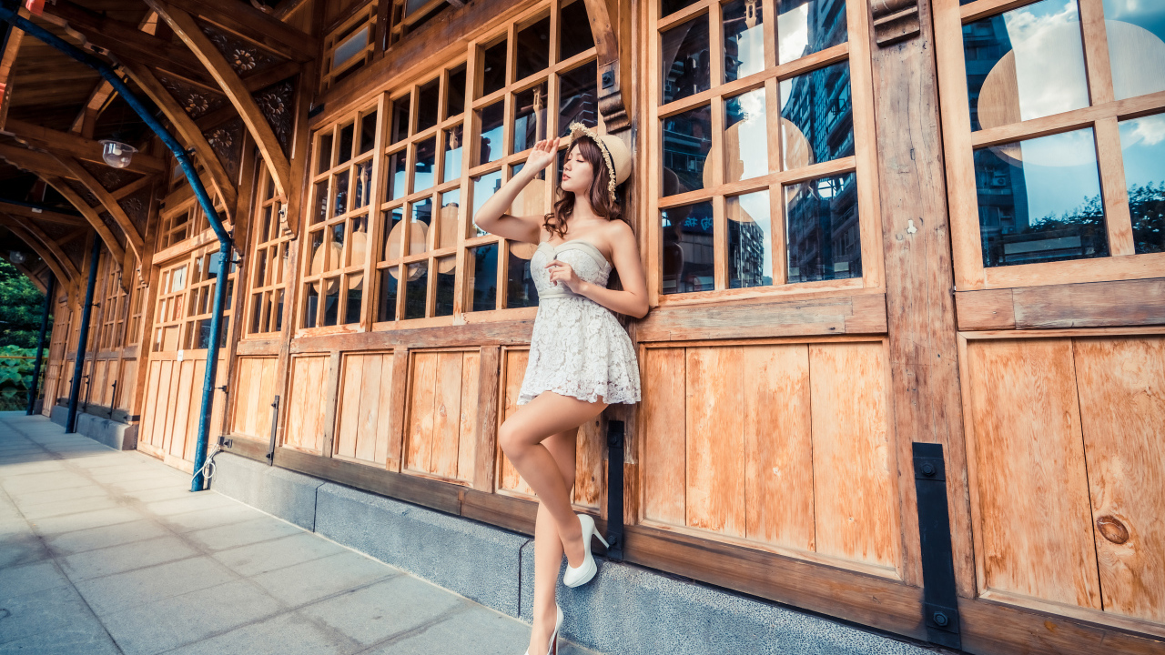 Красивая азиатка в платье стоит у окна кафе