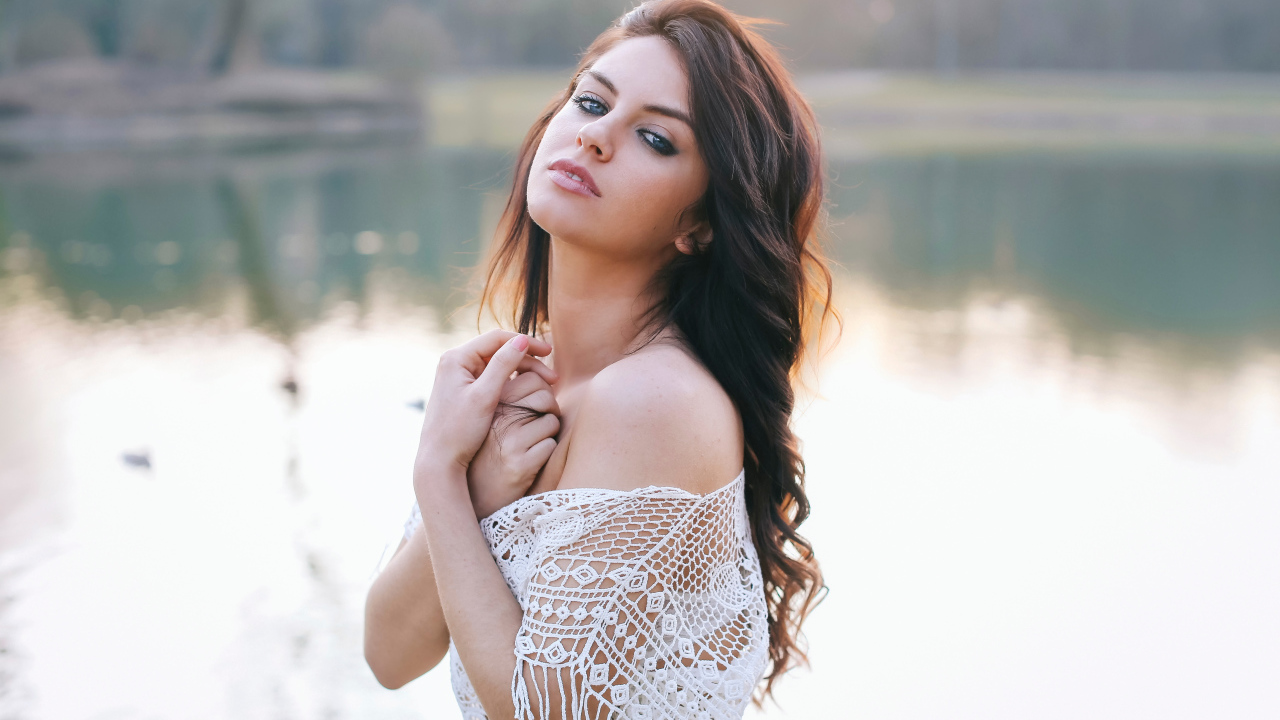 Красивая девушка в белом наряде стоит у озера