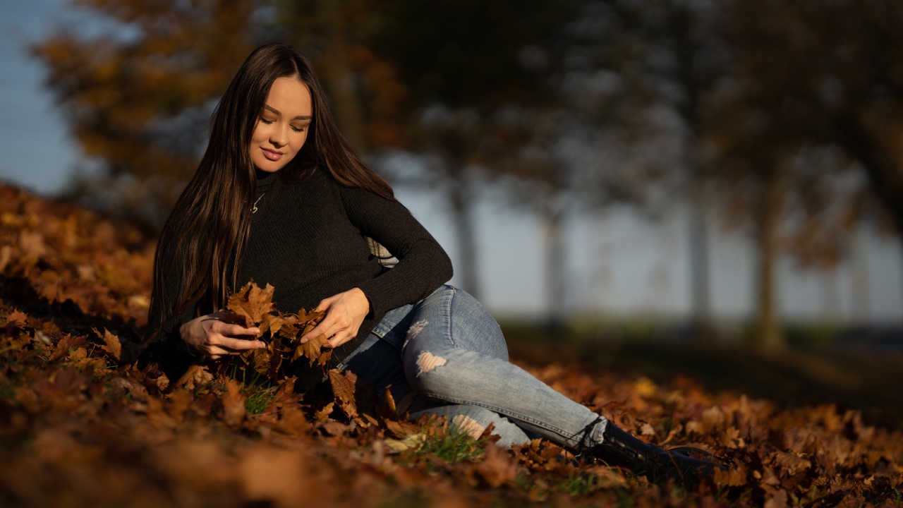 Молодая девушка лежит на опавшей листве