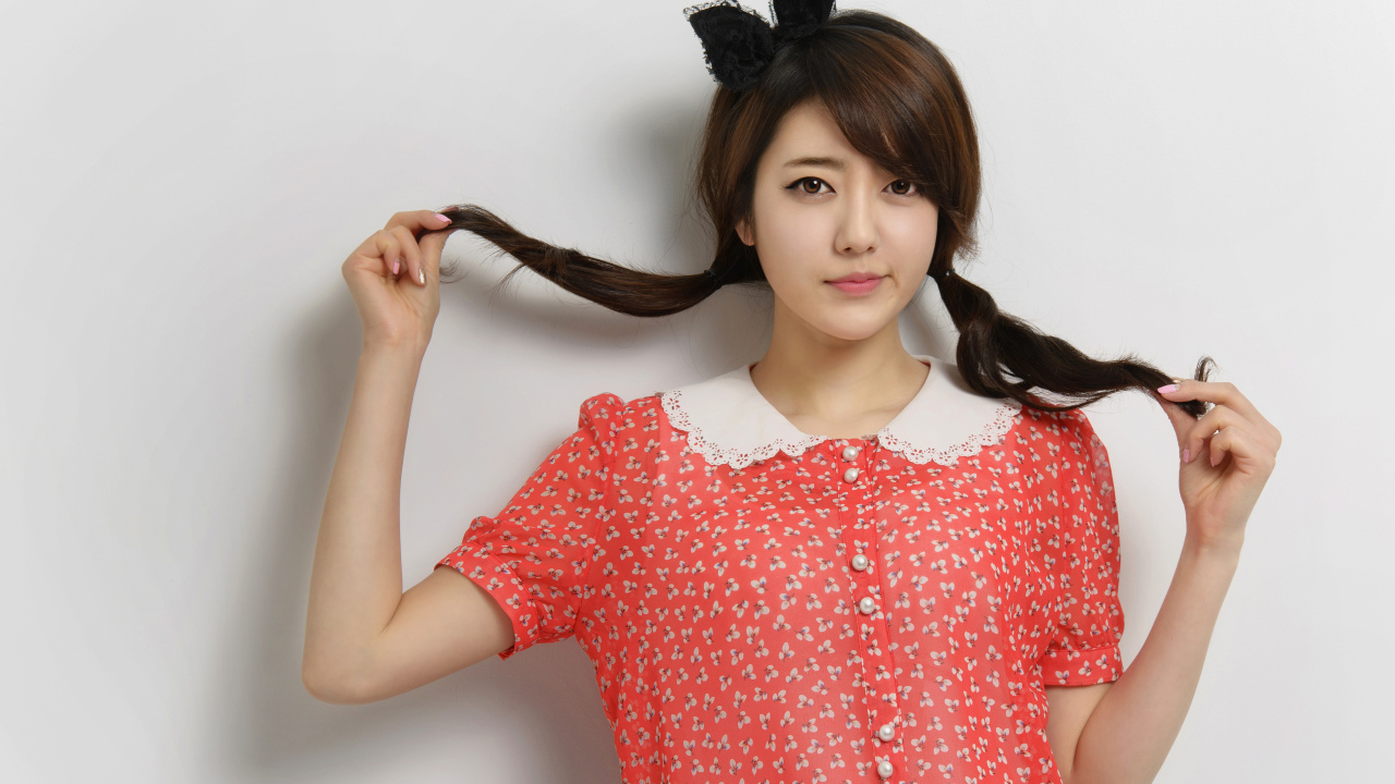 Девушка азиатка в платье стоит у стены 