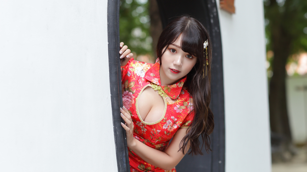 Девушка азиатка в красном платье стоит в арке