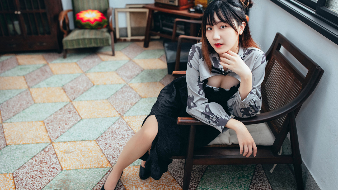 Девушка азиатка сидит на стуле в комнате 