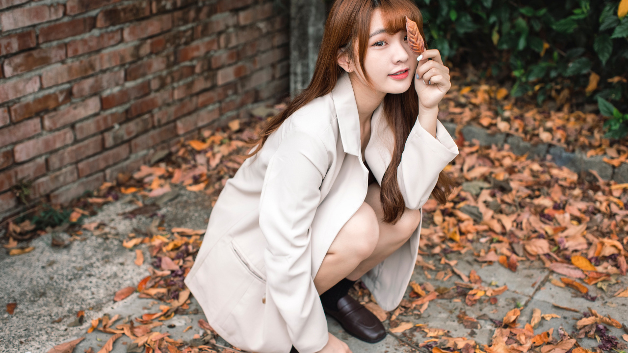 Красивая девушка азиатка на земле с опавшей листвой 