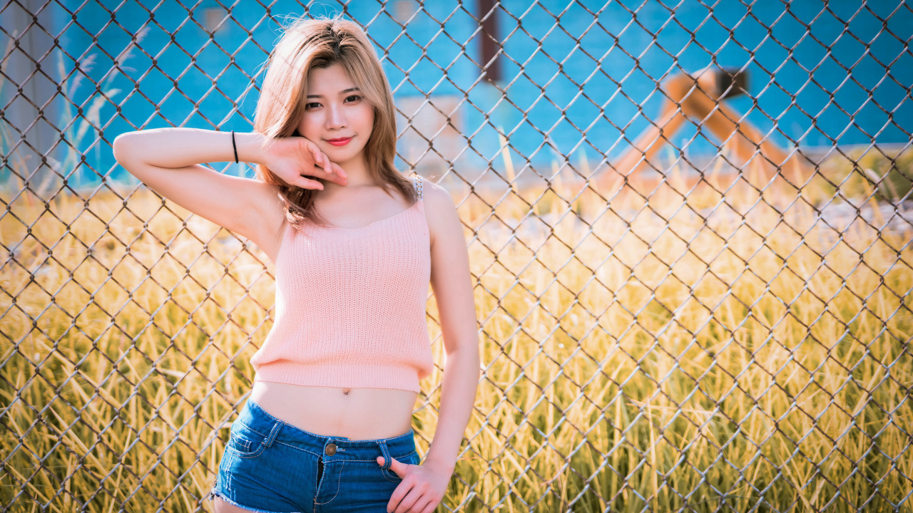 Красивая девушка азиатка стоит у железной сетки