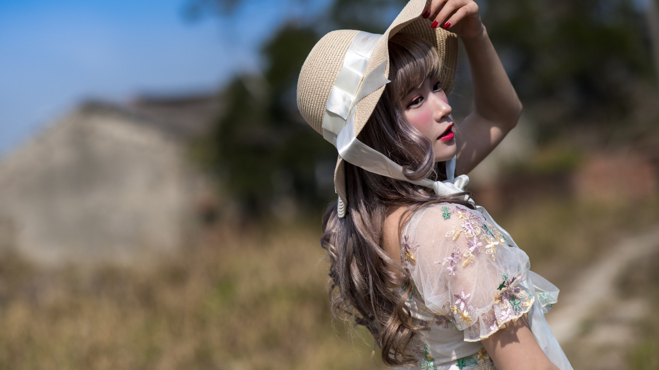 Красивая азиатка в шляпе в лучах солнца