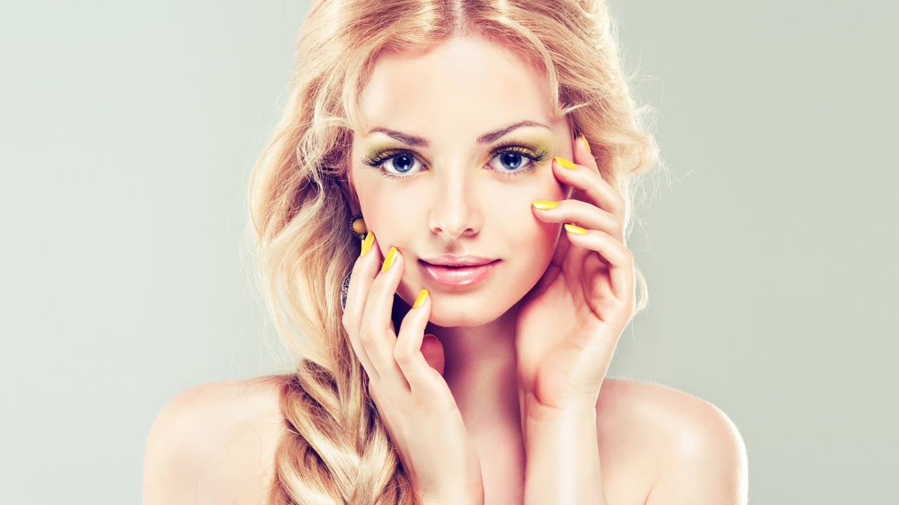 Красивая голубоглазая блондинка с желтым маникюром на руках 