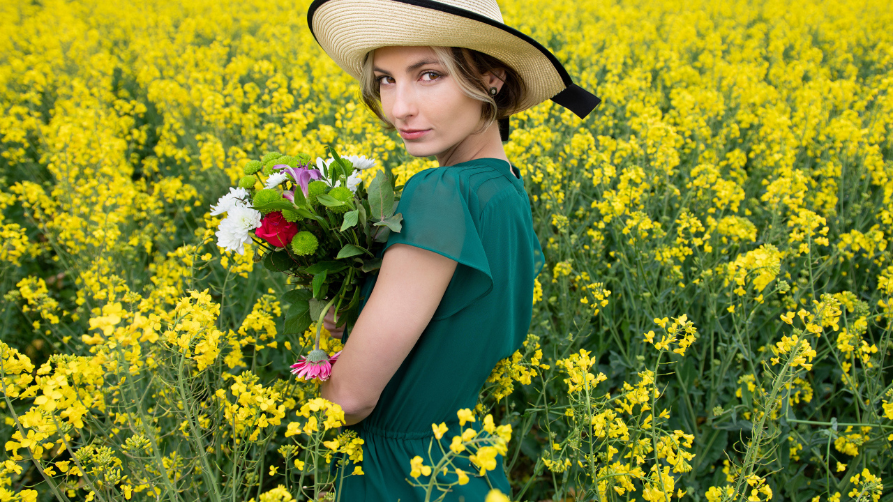 Красивая девушка в шляпе на поле с желтыми цветами летом
