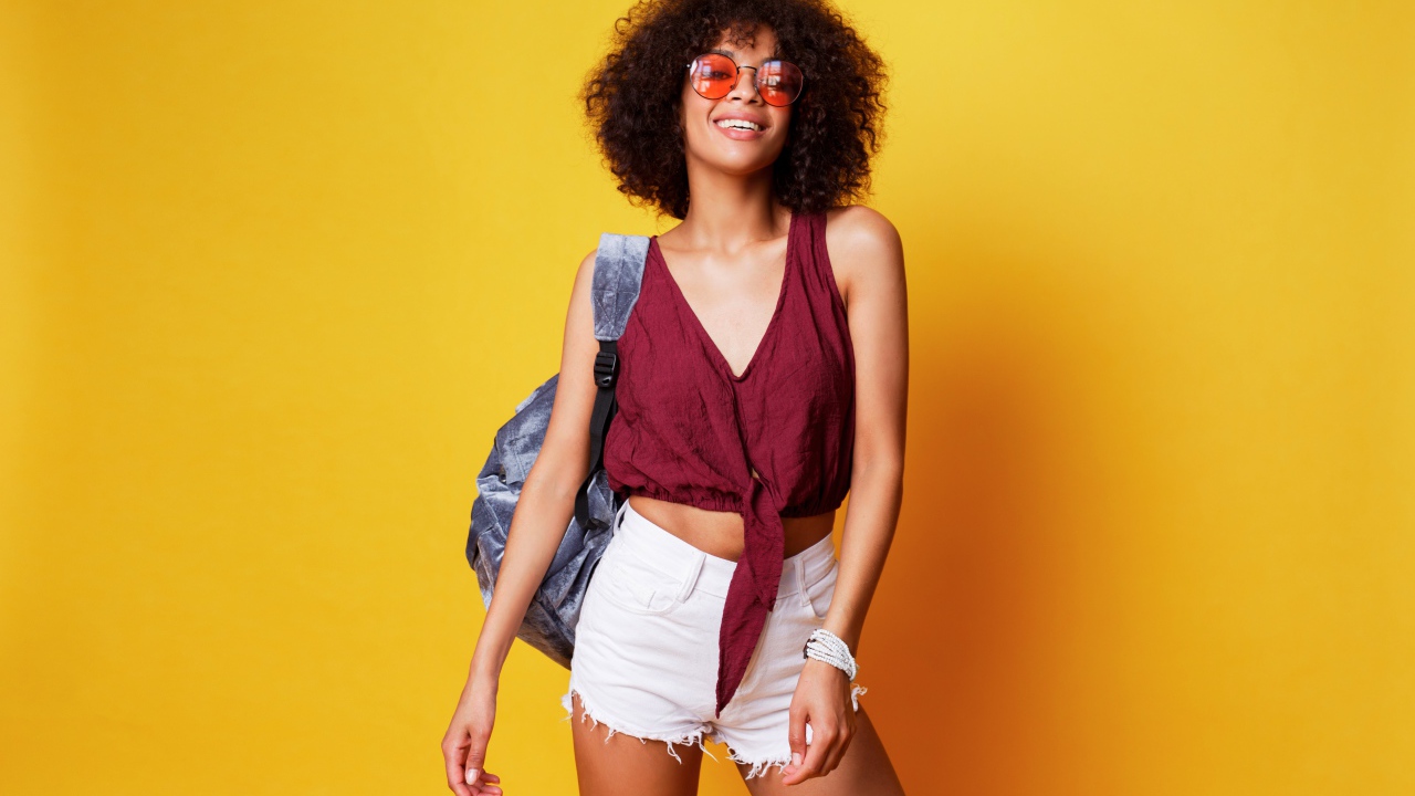 Красивая девушка в очках с рюкзаком на желтом фоне 