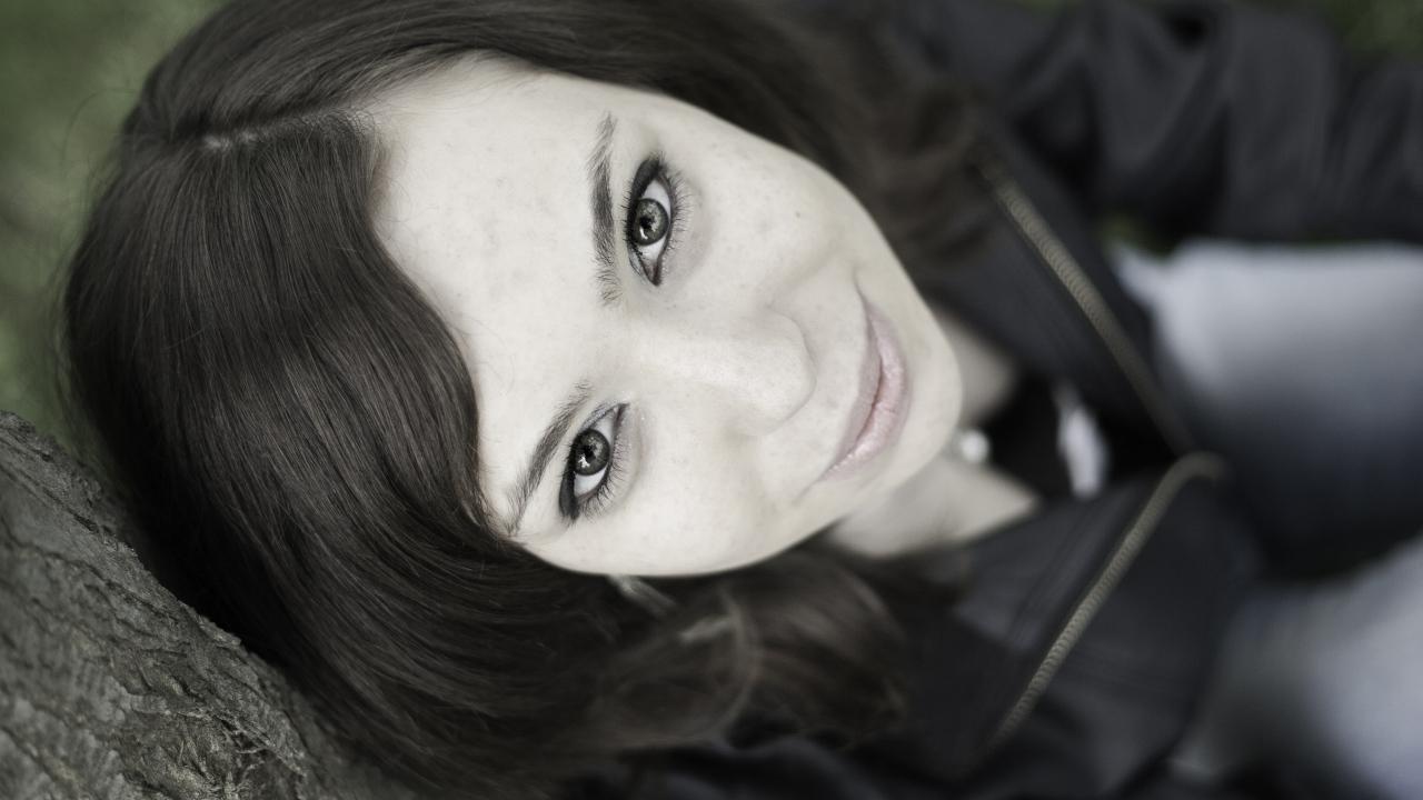 Красивая девушка смотрит вверх сидя под деревом  